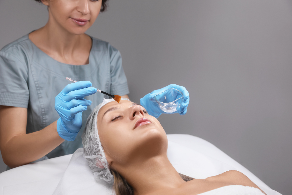 A dermatologist carefully applying a professional peel solution to a client's face in a clinical setting.